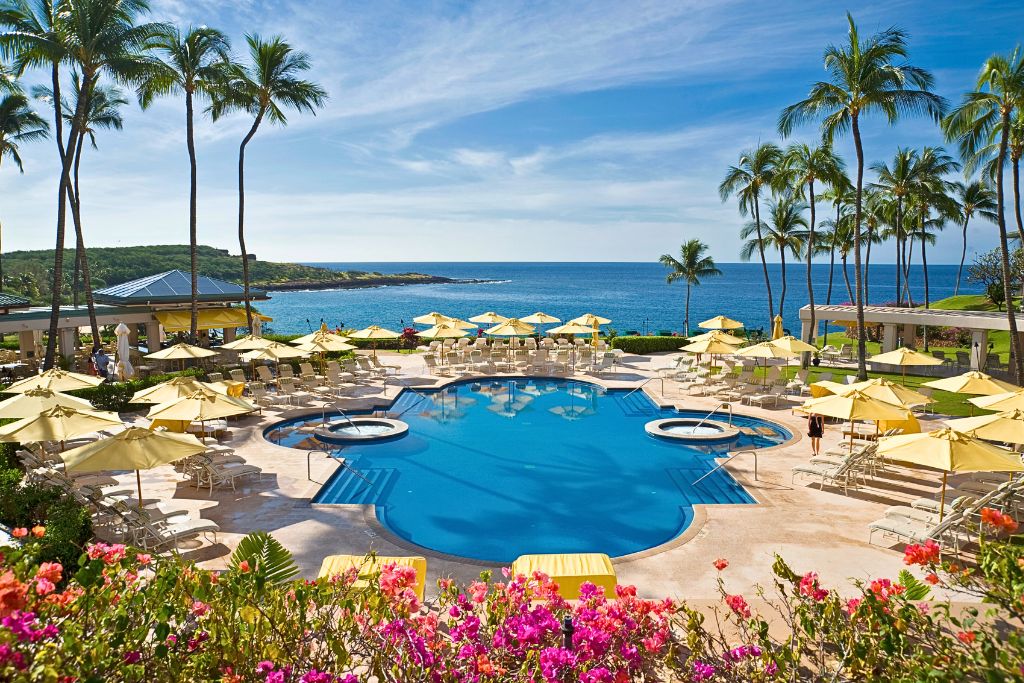 A luxurious resort with a pool and cabanas overlooking the ocean in Hawaii