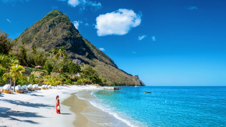 Woman in a red dress on a white sand beach in St. Lucia under the Pitons