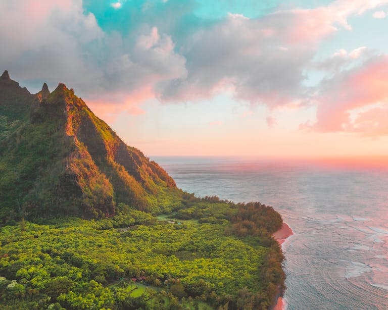 Breathtaking view of Kauai's lush greenery and ocean at sunset, with vibrant colors and dramatic landscapes.
