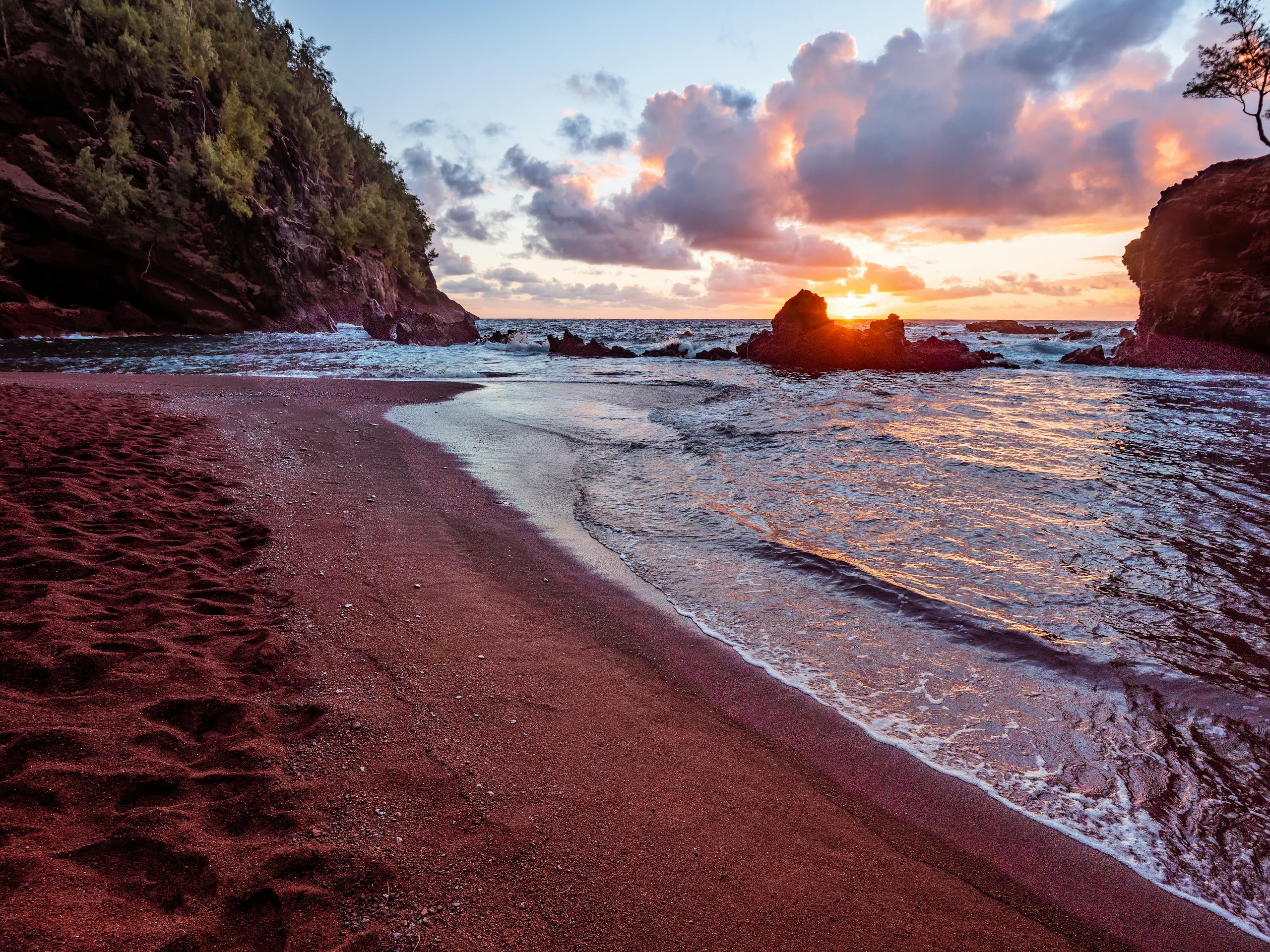 Discover the stunning sunrise over Kaihalulu Beach's unique red sands in Hana, Hawaii.