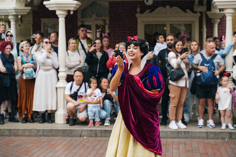 Snow White entertains a crowd with joyful gestures.